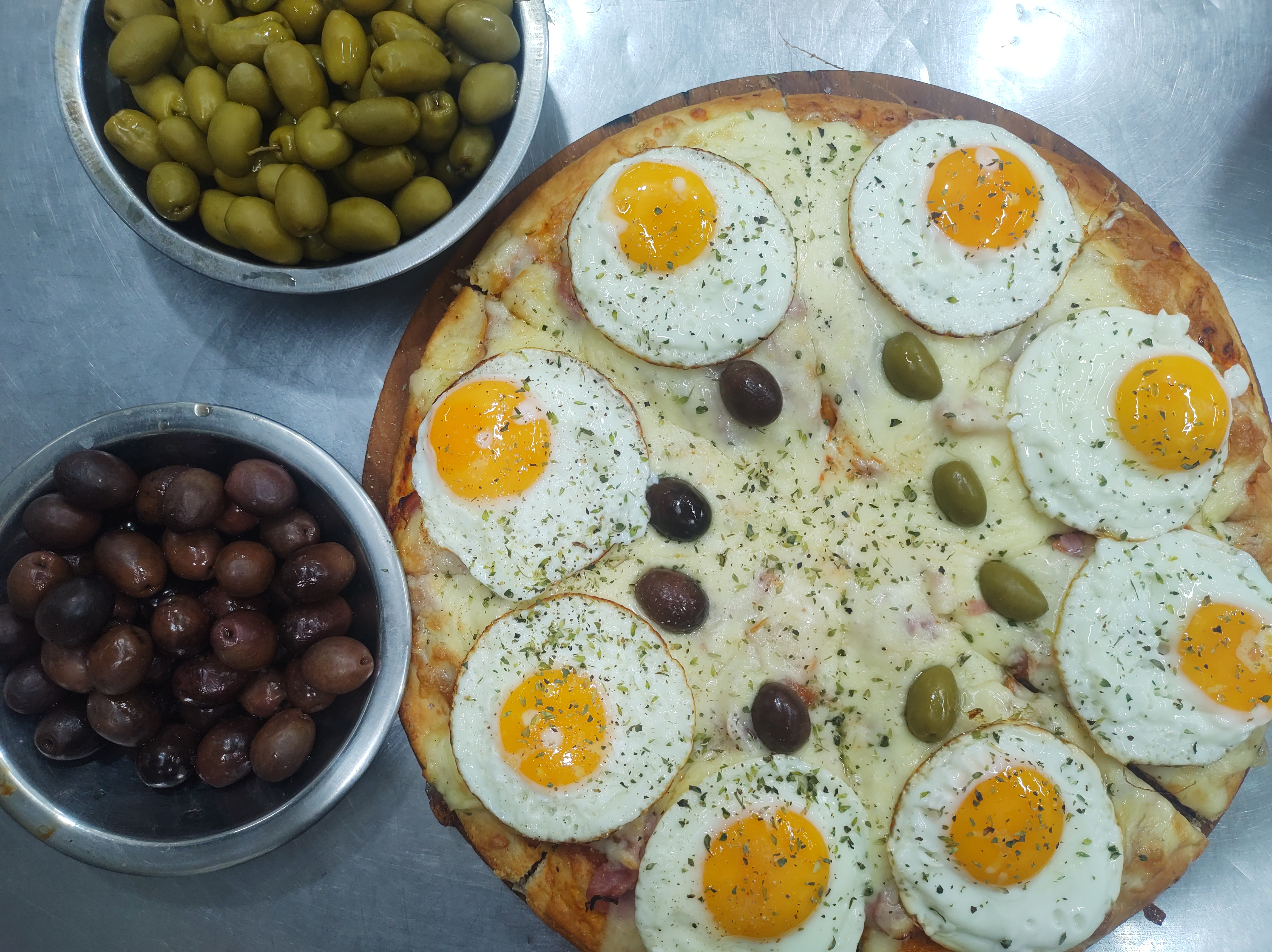 Pizza with fried eggs and olives