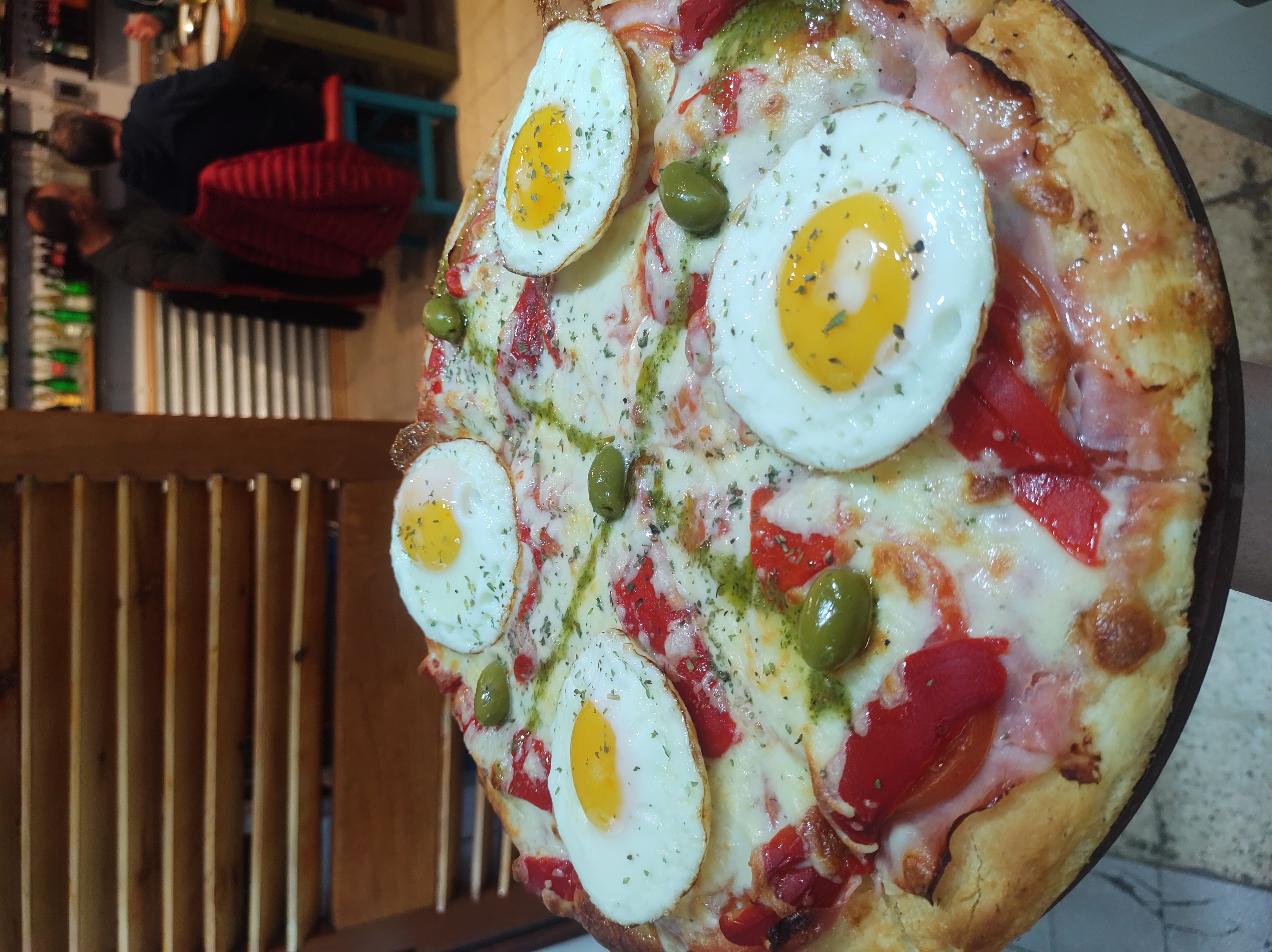 Pizza with eggs and olives at the bar